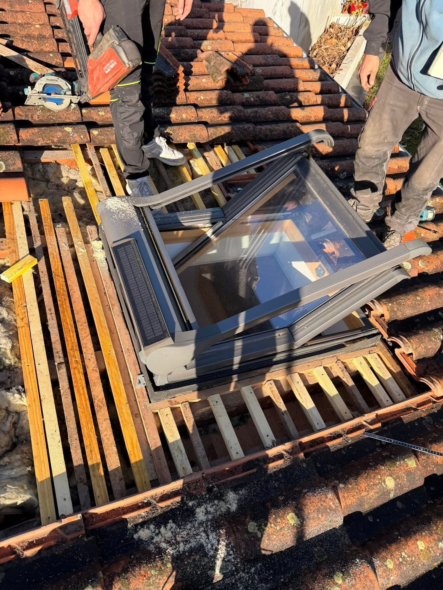 Artisans couvreurs installant une fenêtre de toit sur charpente